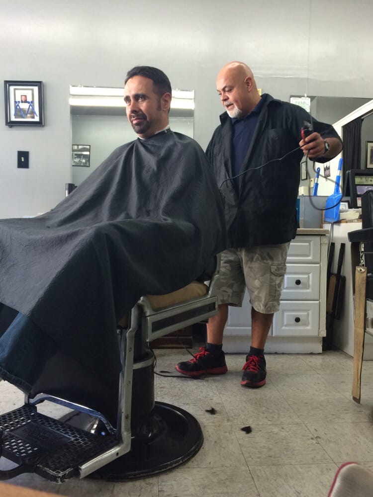 Ray, the owner of Ray's Barber Shop, cutting a customer's hair in the shop