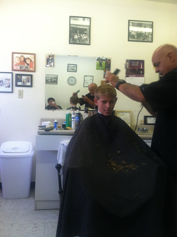 Inside Ray's Barber Shop, with Ray cutting a young customer's hair in front of the mirror